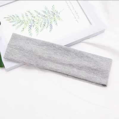 Jlynx soft gray stretch fabric flexible workout headband laid flat on white surface next to frame